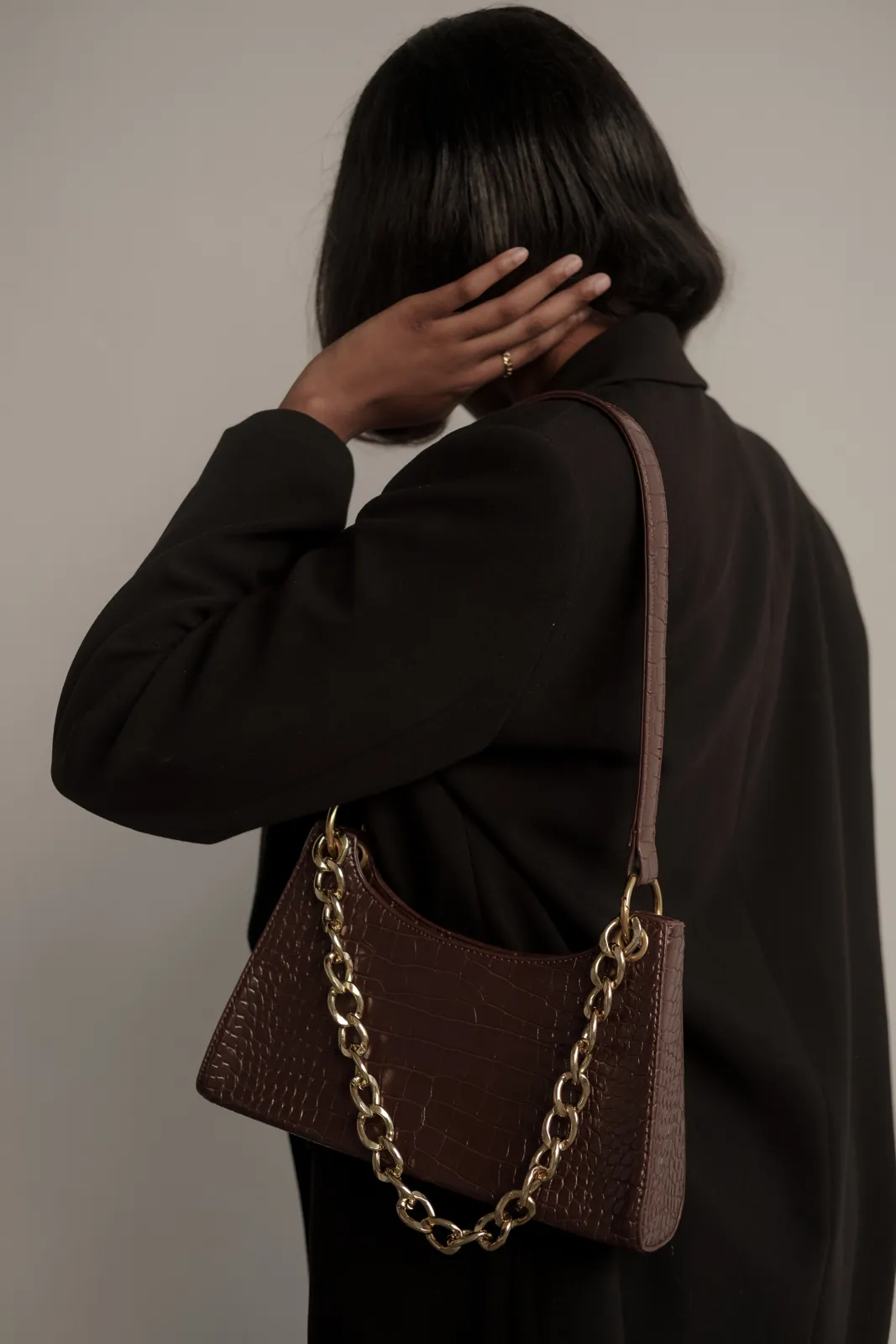 Model in schwarzem Mantel mit brauner Ledertasche – KI-gestütztes Kampagnenbild